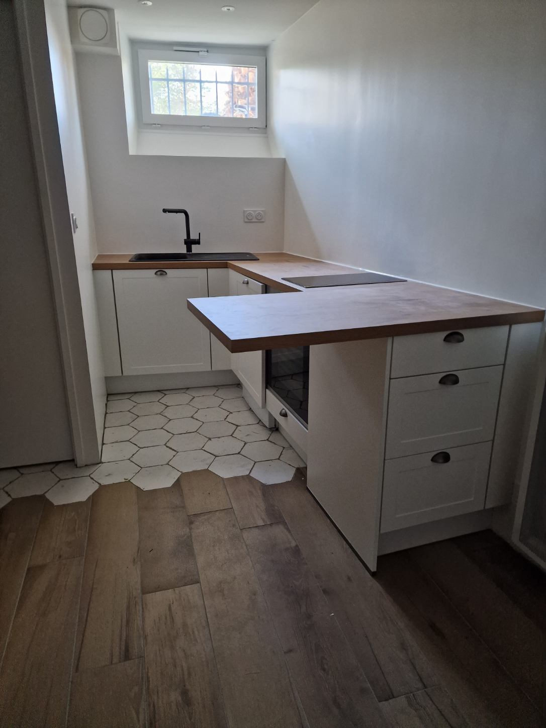 RENOVATION D’UN APPARTEMENT A BIARRITZ Cuisine moderne avec un plan de travail en bois, évier, et électroménagers intégrés.