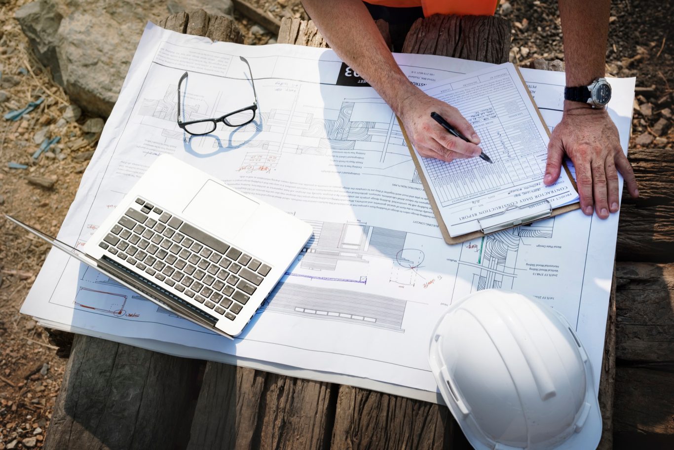 TOUT SAVOIR SUR L'ETUDE DE SOL AVANR LA CONSTRUCTION DE SA MAISON Un plan de construction, un ordinateur portable, des lunettes et un casque sur une table.
