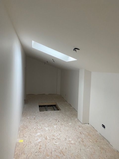 AMÉNAGEMENT DES COMBLES À BASSUSSARRY Intérieur d'une pièce en cours de rénovation, avec un plafond incliné et une lucarne.