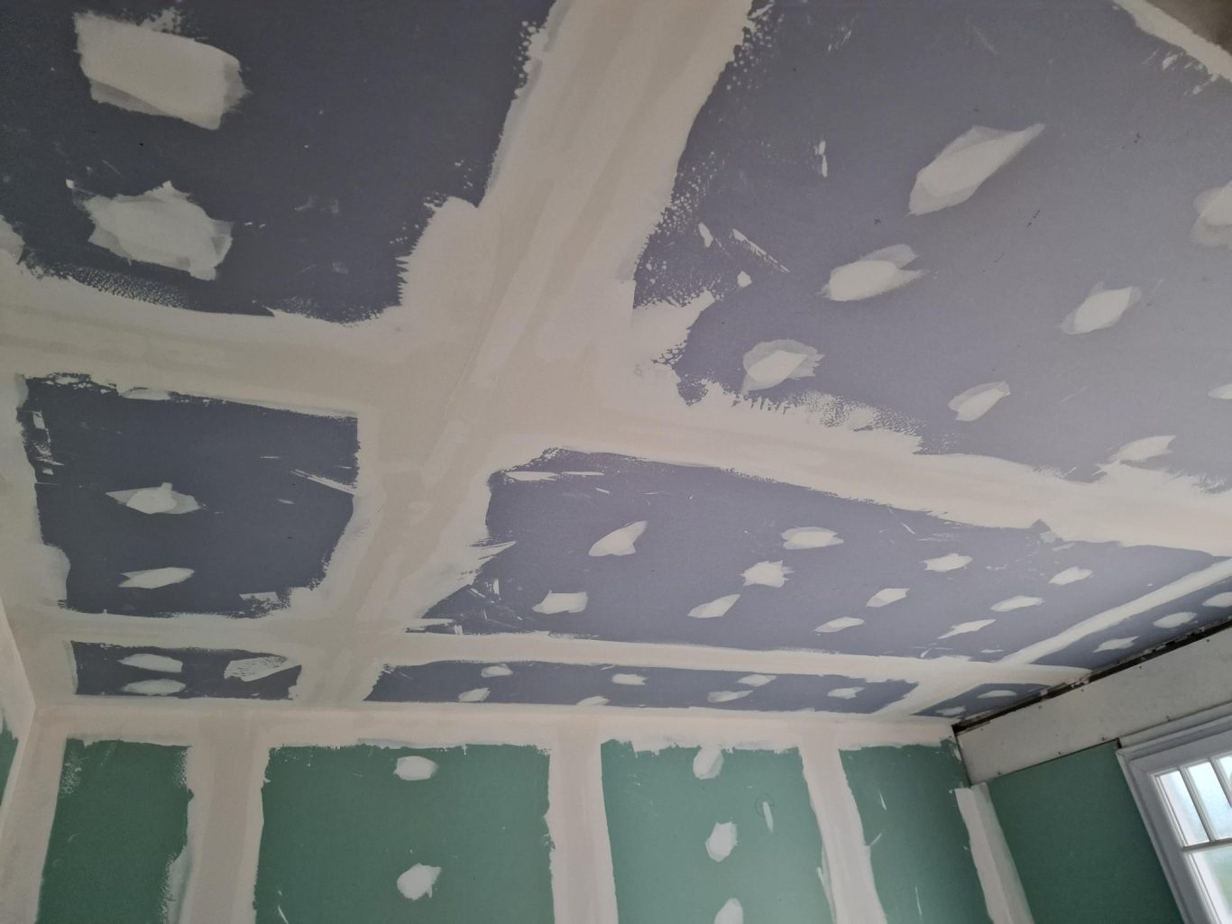 Installation d'un faux plafond Plafond en cours de finition avec des bandes de peinture blanches et bleues.