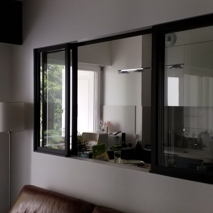 Verrière atelier Vue d'un intérieur moderne avec un mur vitré et un canapé en cuir.